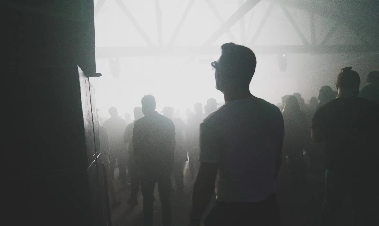 Dancers in silhouette against white fog at a 6AM warehouse event